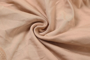 Vue macro du tissu en maille côtelée nude montrant la texture et les détails de couture