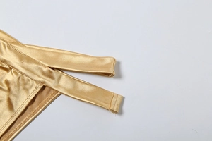 Vue détaillée de la texture du tissu métallique doré brillant et des coutures fines du bikini