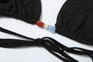 Detail of black bikini top featuring ethnic style beads and textured drawstring fabric