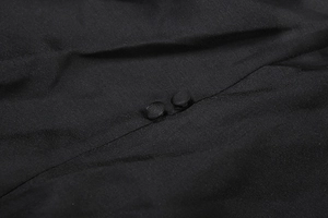 Gros plan sur le tissu en satin noir de la robe avec deux boutons recouverts de tissu