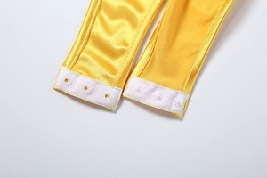 Close-up of bright yellow satin fabric with three white snap buttons at the bottom hem
