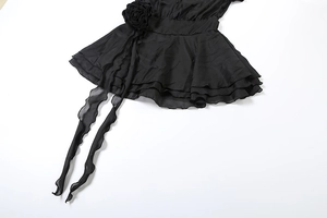 Détail d'une robe noire ornée d'une rose en relief et de volants superposés élégants