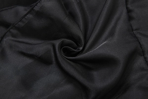 Détail du tissu en satin noir lisse avec un drapé souple et un éclat soyeux élégant