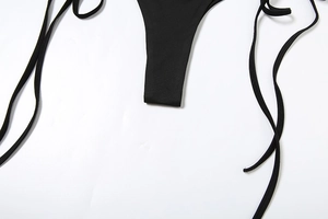 Detailed view of the black bikini bottom featuring thin adjustable side tie-up straps
