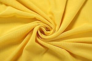 Macro shot of bright yellow piqué knit fabric with spiral pleats and breathable texture