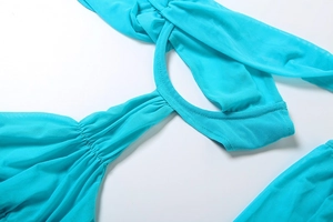 Détail du tissu en maille transparente turquoise avec plis et découpes circulaires sur la robe
