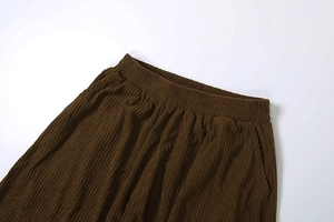 Detail of high waisted loose pants showing vertical corduroy texture and elastic waistband