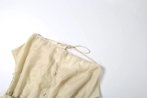 Détail de mini robe fleurie dos nu montrant le tissu mousseline beige et le nœud délicat