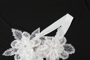 Macro shot of white lace floral headband with sequins and rhinestone on black background