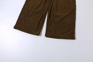 Detailed macro view of dark brown corduroy fabric texture on straight leg trousers