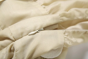Détail de la fermeture éclair invisible sur une robe en satin de couleur champagne
