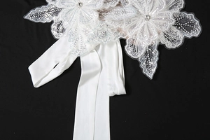 Macro detail of white bridal lace flowers with sequins and satin ribbon on black background
