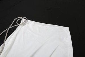 Detail of white semi-transparent fabric featuring elegant rhinestone braided strap accents