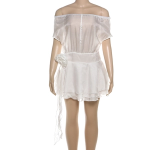 Détail de robe blanche à épaules dénudées avec fleurs 3D et ourlet à volants