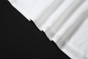 Detailed macro view of white fabric with vertical stripe texture and neat hemline stitching