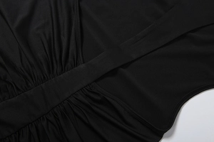 Dettaglio dell'elegante scollatura incrociata con pieghe arricciate su un abito nero