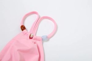 Detail of pink bikini strap with three colorful oval beads and smooth stitching on fabric
