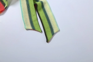 Détail d'une bande tricotée style bohème avec motif de rayures zigzags vert et rouge