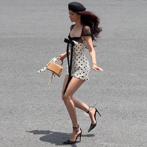 Polka dot mini dress featuring black lace trim and a large bow accent for summer style