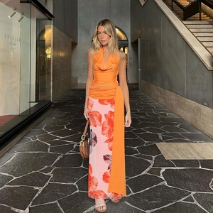 Detail of orange satin halter top and vibrant floral maxi skirt set in an outdoor setting