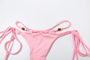 Detail of pink tie-side bikini bottom with colorful beads and elastic mesh fabric
