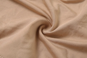 Détail macro du tissu en maille côtelée nude montrant une texture douce et extensible
