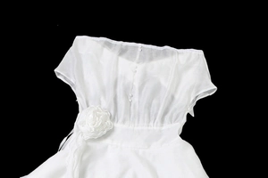 Détail de la robe blanche à fleurs en organza et boutons décoratifs sur le buste