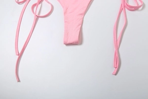 Detail of pink bikini bottoms featuring side tie strings and smooth elastic fabric