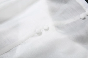 Détail macro de la texture du tissu en mousseline blanche et boutons recouverts assortis