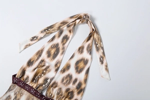 Détail de la robe en satin léopard avec liens de cou et ruban décoratif à pois blancs