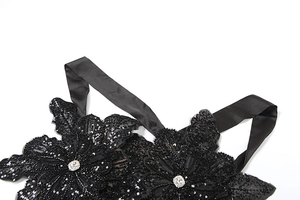 Detail of black sequined floral appliques with rhinestones on a satin strap top