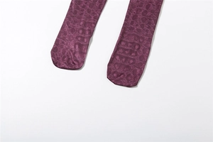 Dettaglio di leggings viola con trama a coccodrillo e finitura lucida a rilievo