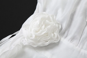 Détail d'une grande fleur en tissu 3D et de pétales délicats sur une robe d'été blanche