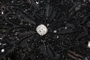 Detailed macro view of handmade black sequin flower applique with sparkling rhinestone center