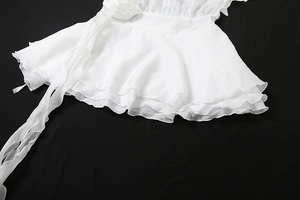 Détail de l'ourlet à volants trois épaisseurs et fleur 3D sur robe en mousseline