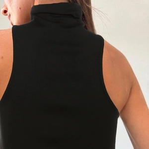Close-up of black ribbed knit high-neck sleeveless top showing back detail and racerback cut
