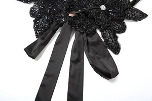 Macro detail of black sequin flower belt with a sparkling central crystal on satin ribbon