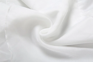 Vue détaillée du tissu en mousseline blanche légère avec des volutes et coutures fines