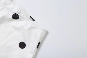 Close-up of white fabric with large black polka dots and high-quality stitching details