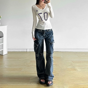Detailansicht weißes V-Ausschnitt-Strickoberteil mit 70-Druck und blauer Cargo-Jeans
