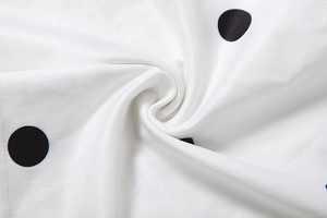 Macro detail of white polka dot fabric with smooth texture and subtle silky sheen finish