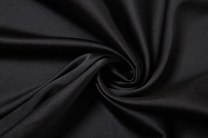 Macro shot of high-quality black satin fabric with silky texture and elegant draped folds