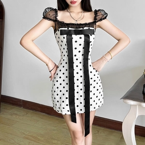 Detail of summer polka dot mini dress featuring a large black bow and lace sleeves