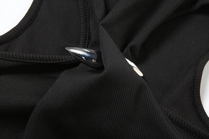 Close-up of black ribbed knit fabric featuring a teardrop silver metal hardware detail