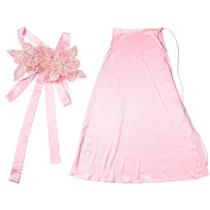 Detail of pink satin skirt set showing sequined 3D flower chest accessory and texture