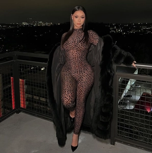 Close-up of leopard print jumpsuit with faux fur trim on a long black coat