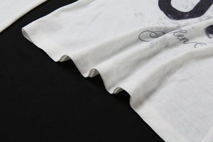 Nahaufnahme der feinen Rippstruktur und des schwarzen Buchstabendrucks auf weißem Langarmshirt
