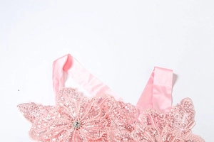 Detail of pink sequined floral applique with beads and rhinestones on satin fabric