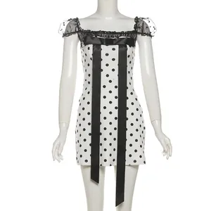 Detailed close-up of polka dot mini dress with black mesh trim and large satin bow decoration