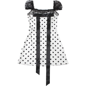 Detailed view of polka dot dress featuring lace mesh sleeves and a large satin bow